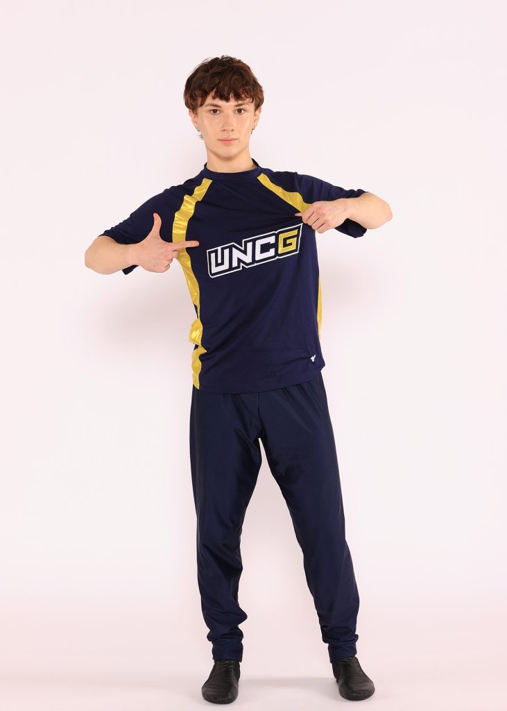 Male dancer in UNCG uniform poses in front of a white background.