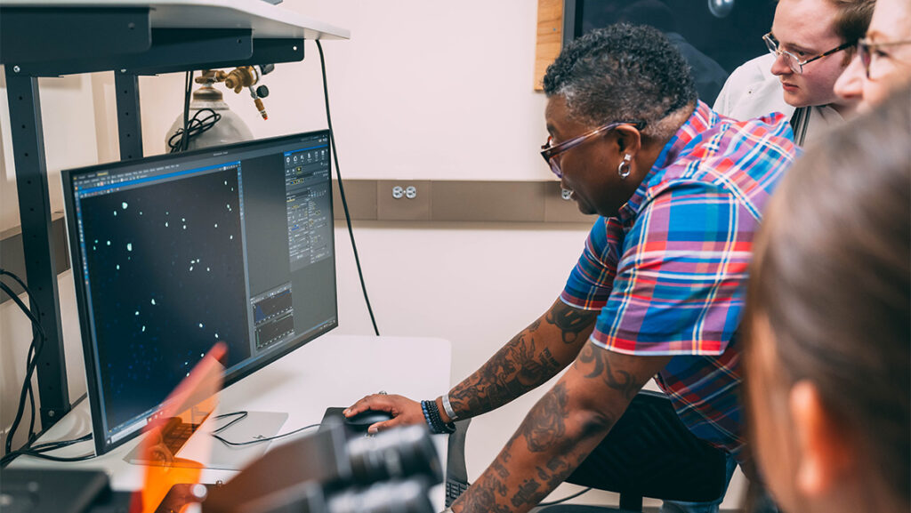 UNCG Research Technician Lee Griffin shows biology students how to use the computer for a microscope.