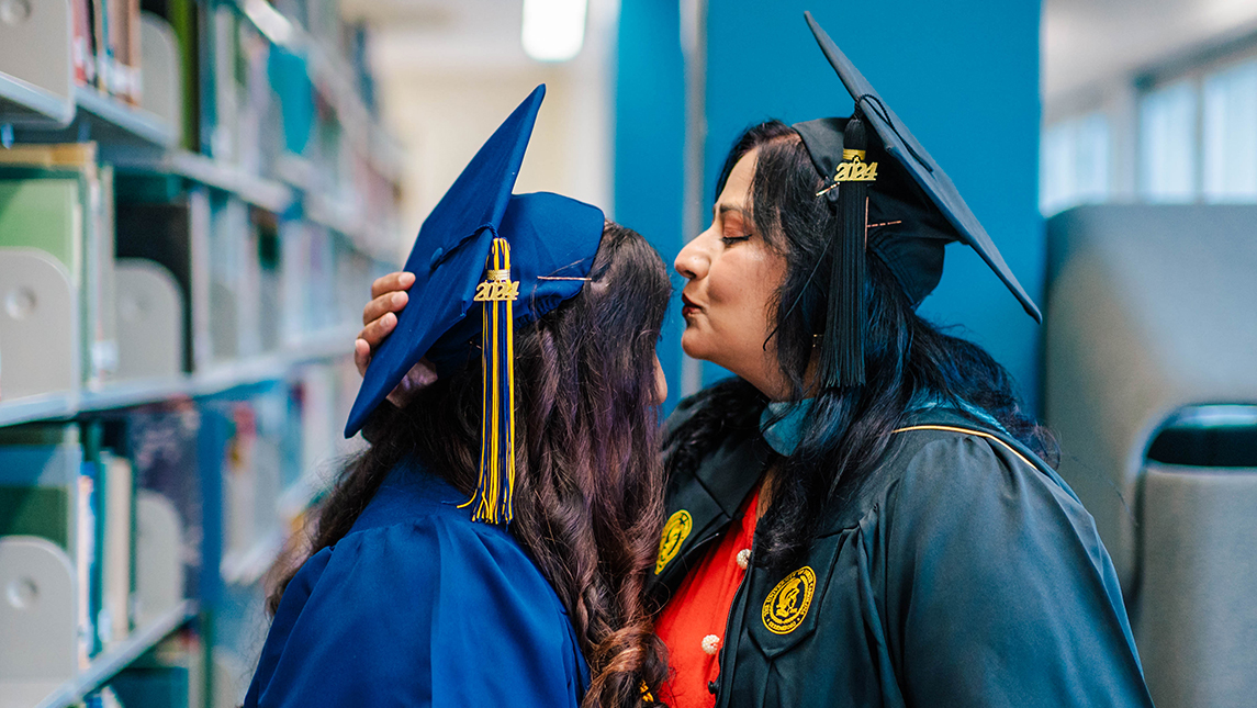 Mother and daughter graduates show affection in library