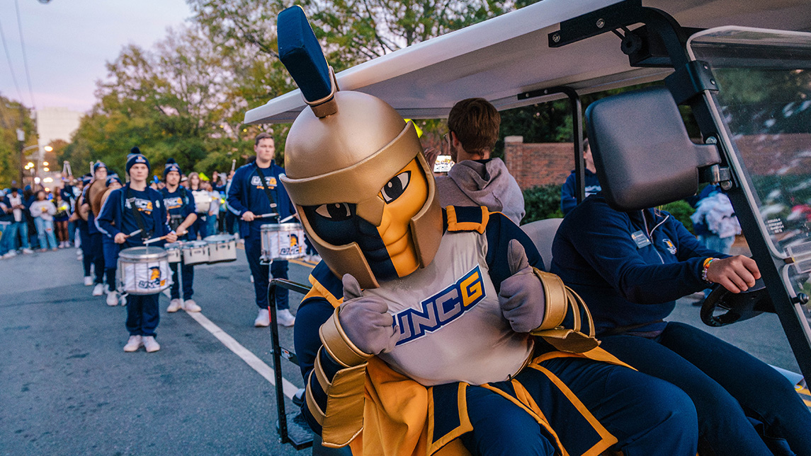 Spiro gives a thumbs up from a golf card with the Storm the Streets parade behind him.