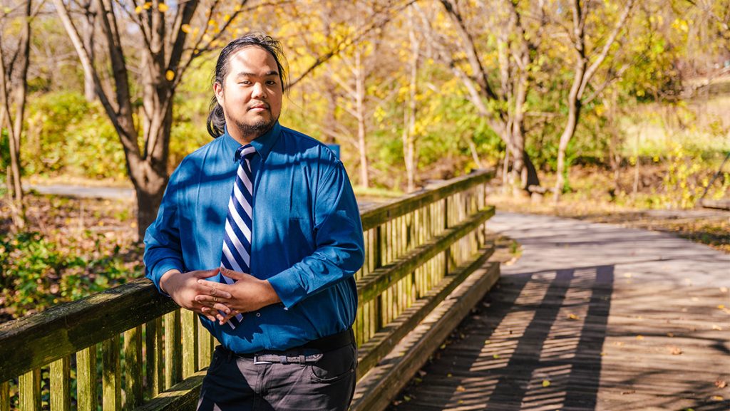 Elijah Resuello leans on the rail of a bridge at UNCG.