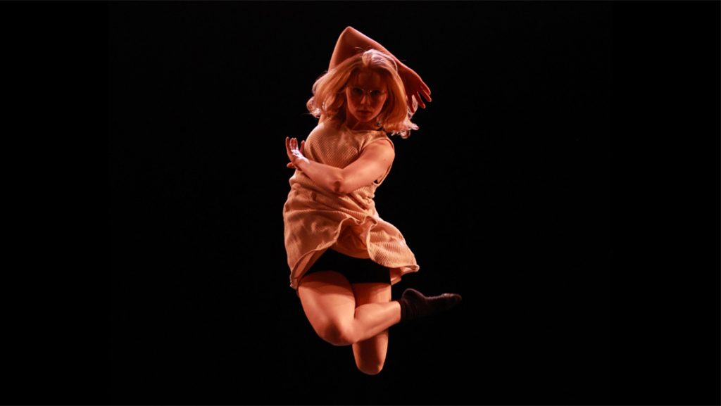 UNCG dance student Anna Clymer mid-leap onstage.