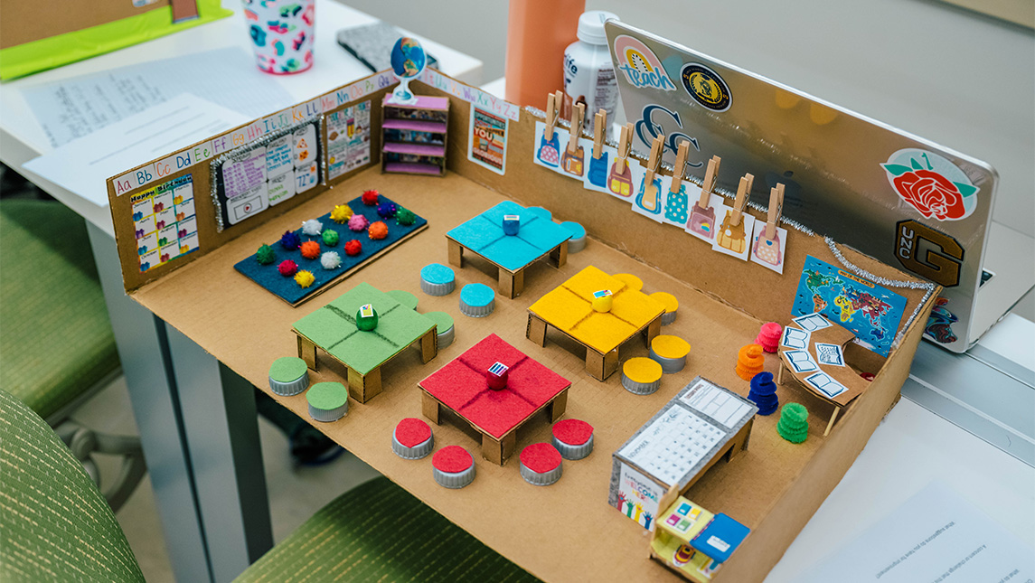 Colorful desks inside a cardboard classroom model.