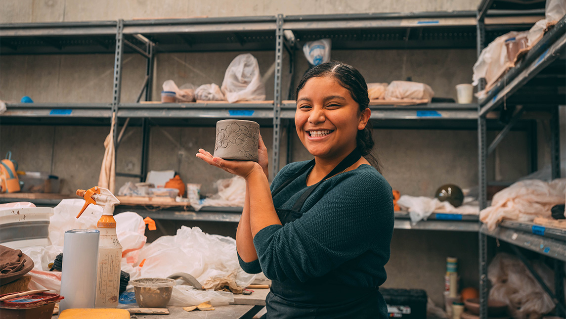A UNCG student holds up her ceramic model.
