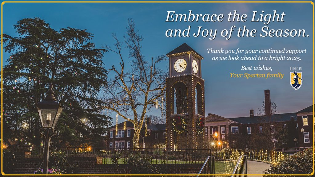 UNCG's 2024 holiday card shows the clocktower draped in lights.