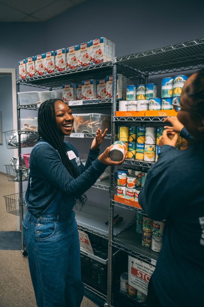 Two student stock shelves in a food pantry.