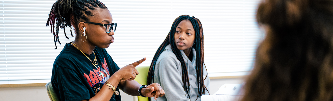 A student uses sign language in a classroom