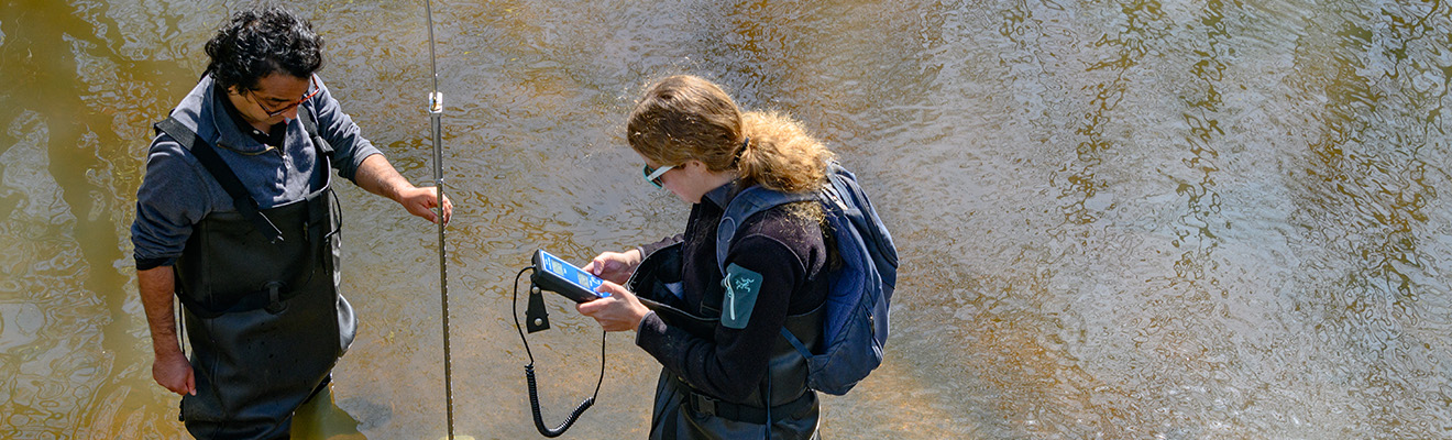 Faculty and student take measurements in creek bed
