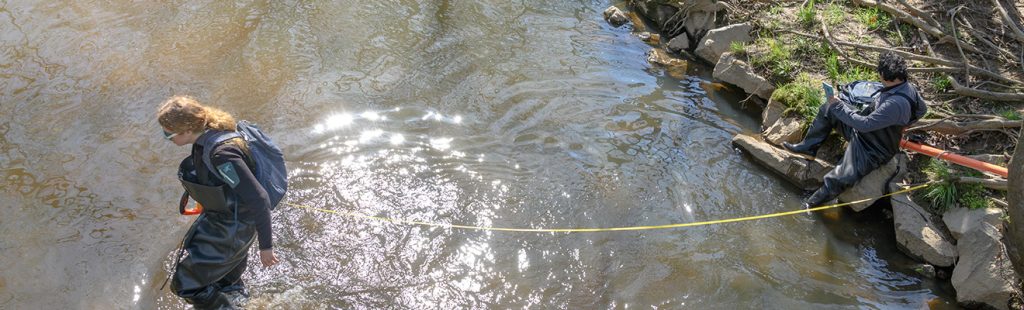 Faculty and student take measurements in creek bed