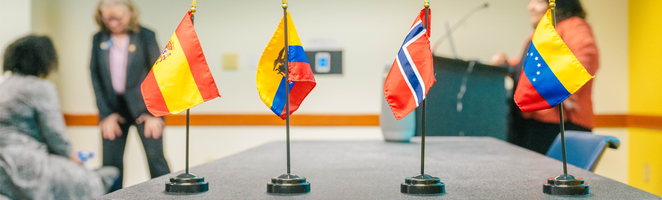 A closeup picture of a conference table with four international flags