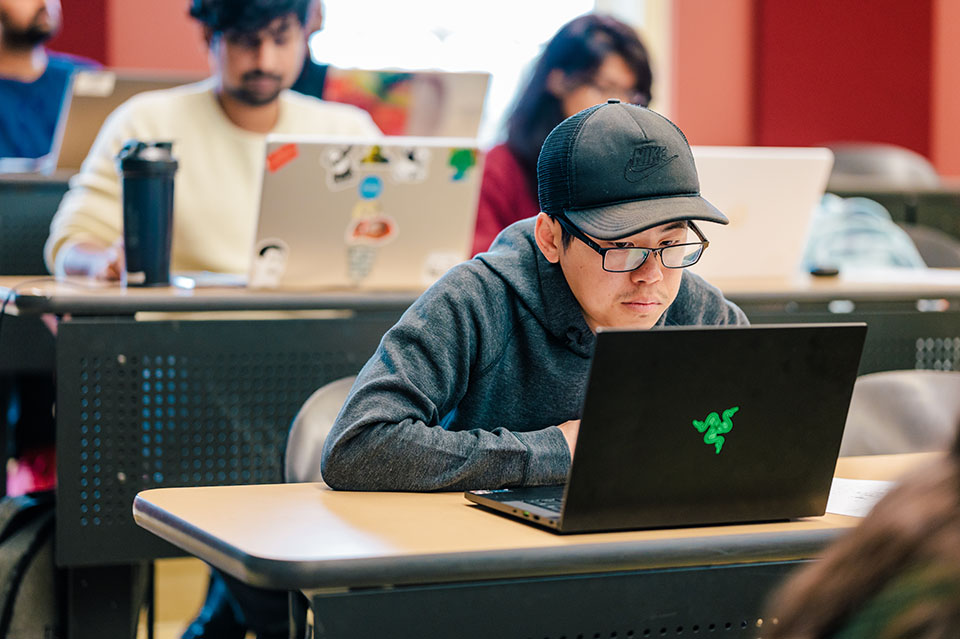 A student looks on at his lap top while sitting in class