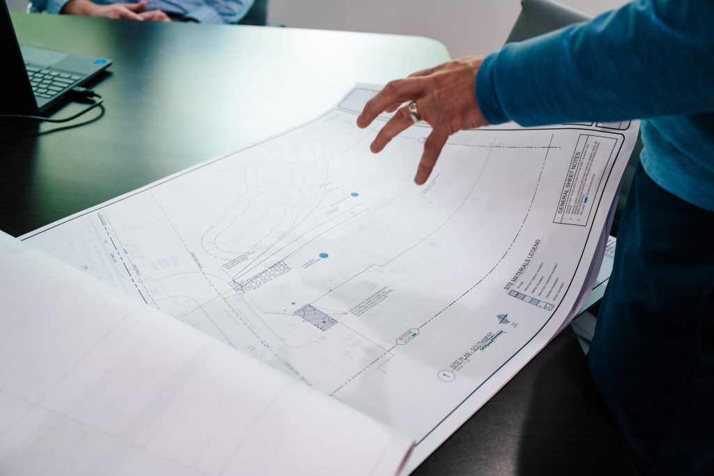 A hand poised over a set of construction blueprints