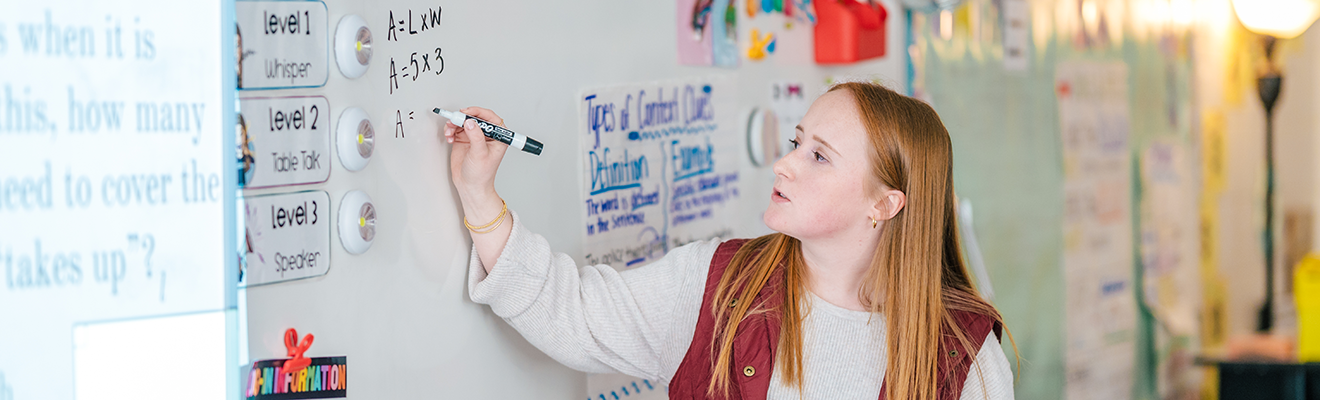 Student teacher Alyssa Dehart works a math problem on the dry erase board