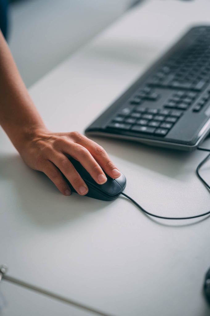 A hand using a computer mouse beside a keyboard