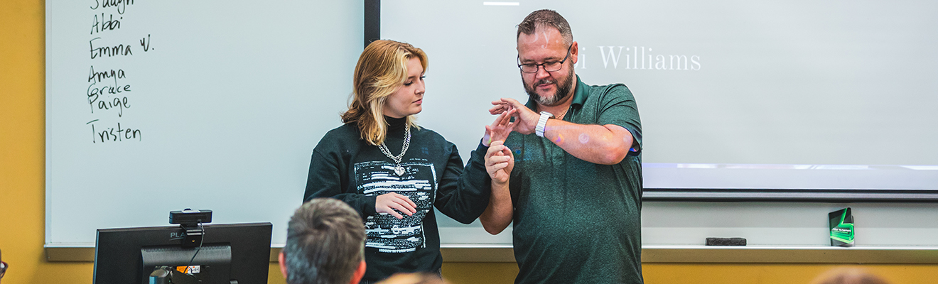 Frank Griffin instructs a student on finger positioning during an ASL lesson