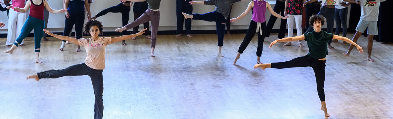 Two dancers spin on one leg in a studio.
