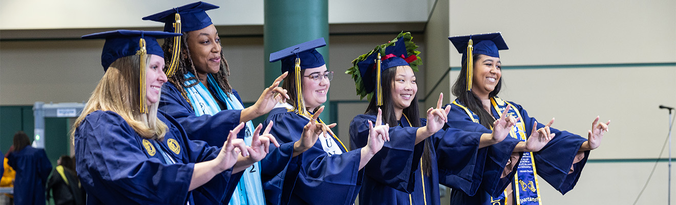 A group of in caps and gowns do sign language.
