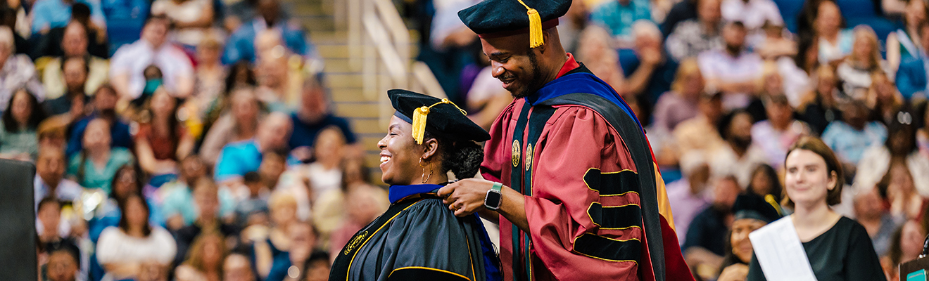 Dr. Jesse Ford hoods a doctoral graduate