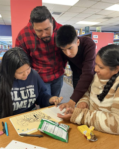 A group of multilingual learners gather around a table