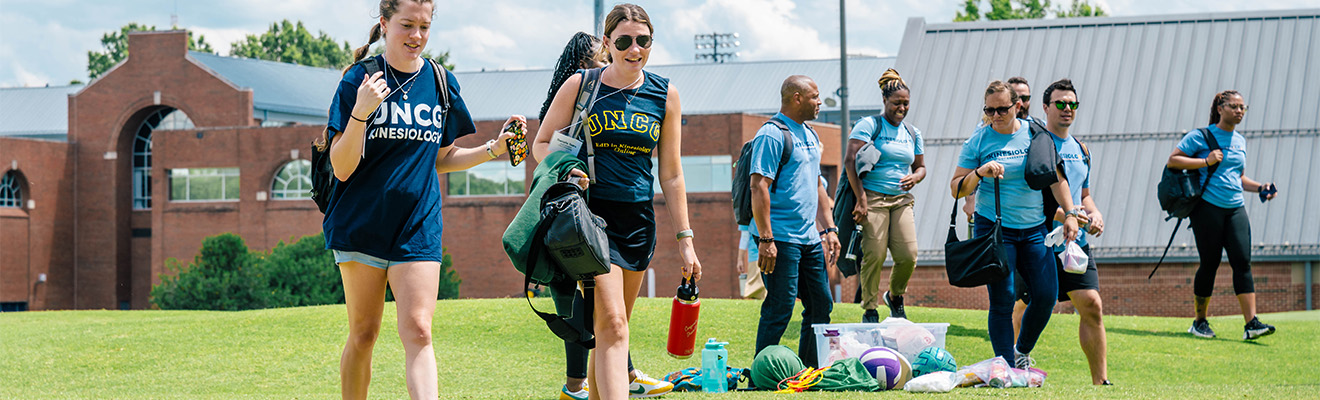 People in gym clothes walk across an athletic field.