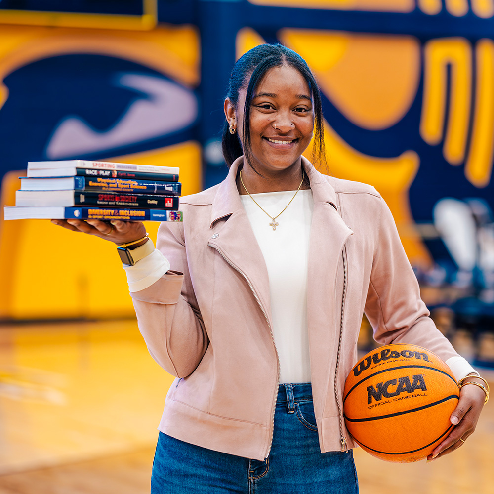 Lexi Kier holds a stack of books in one hand and a basketball in the other.