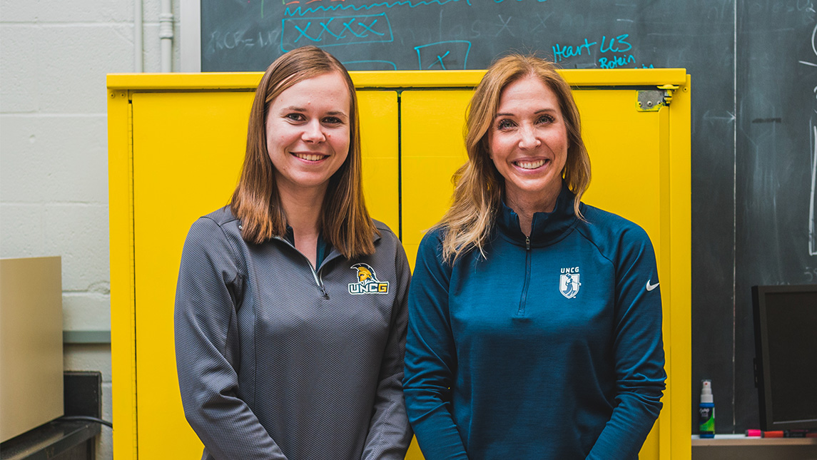 Louisa Tichy and Dr. Traci Parry wearing UNCG-branded sweatshirts.