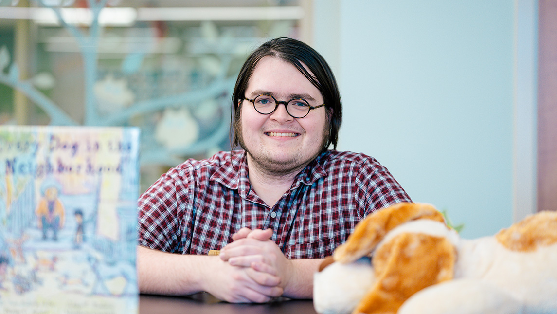 Social studies teacher Luke Vassar sits next to a book and a stuffed animal.