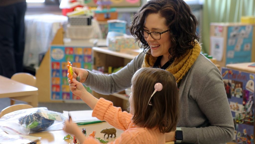 Virginia Madorin works with a young student in a classroom