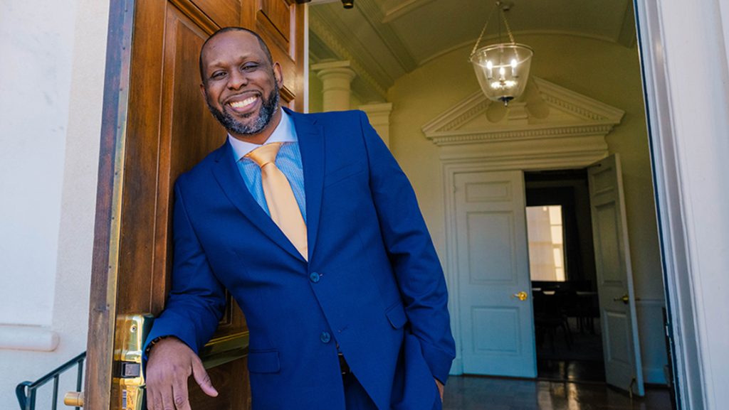 UNCG alumnus Marcus T. Johnson stands at the entrance of the Alumni House.