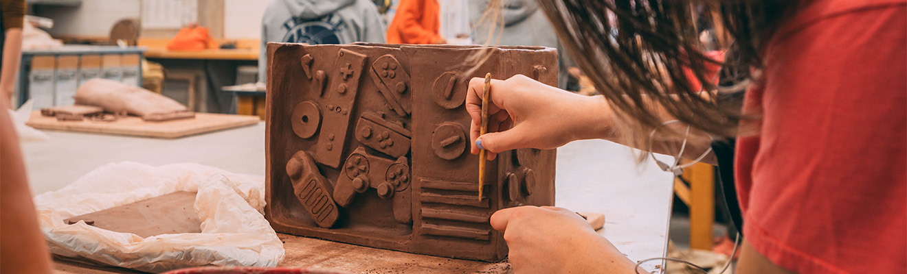 Close-up on a woman carving clay art.