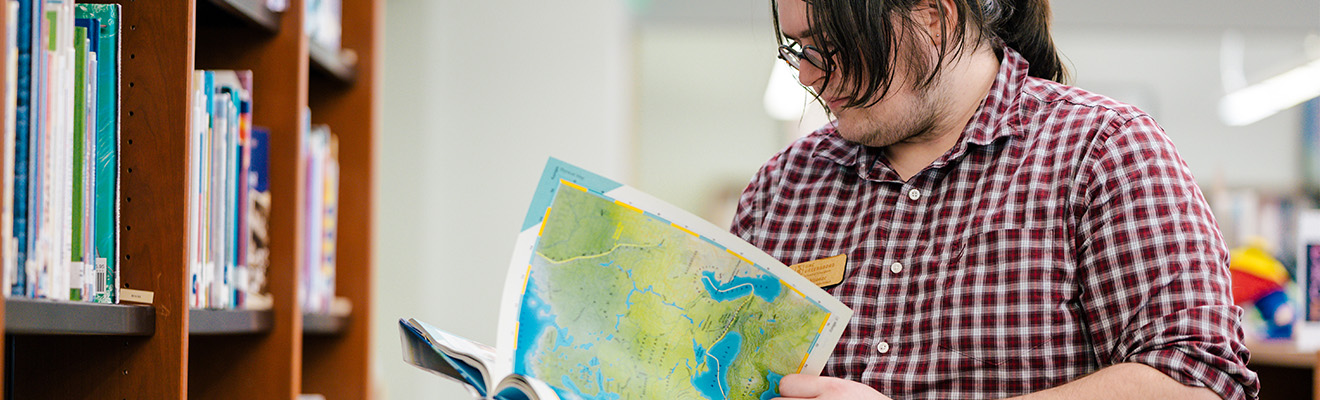 A man leafs through a book of maps.