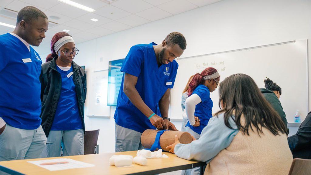A UNCG nursing student practices tightening a tourniquet.