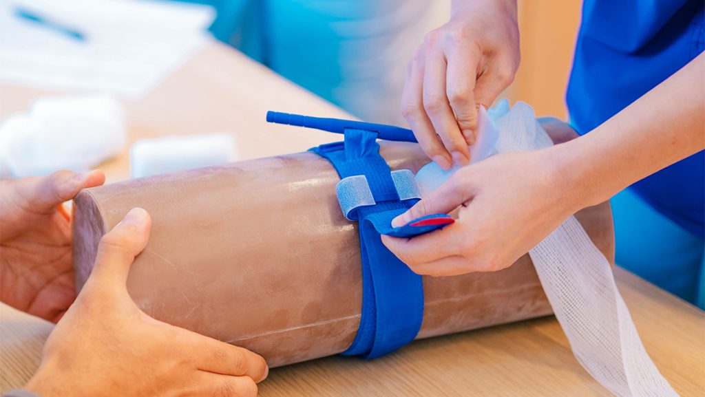 Close-up on a UNCG nursing student applying a tourniquet.