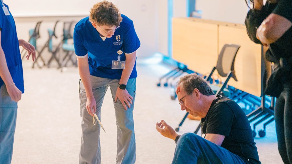 A UNCG nursing student talks to an actor who appears injured in a plane crash.