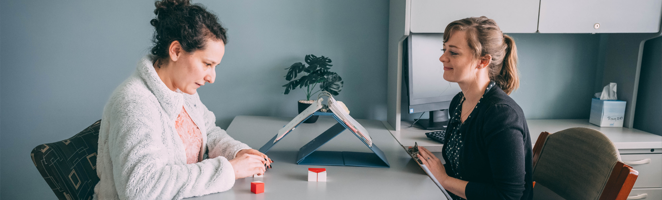A psychology student and instructor set across each other at a desk reviewing techniques.