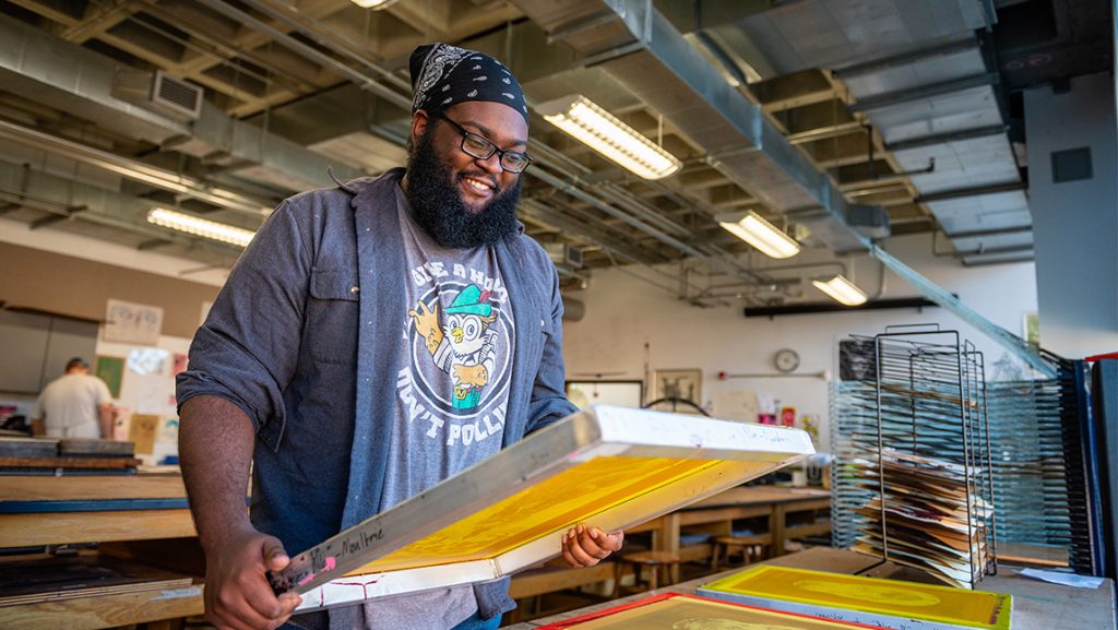 Zaire Miles-Moultrie holds his printed art in the studio.