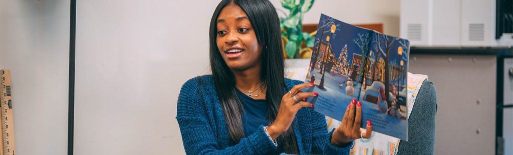 A UNCG student teacher reading a picture book.