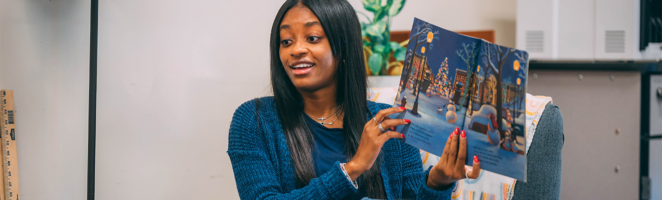 A UNCG student teacher reading a picture book.