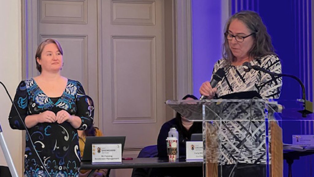 A UNCG staffmember stands by a podium.