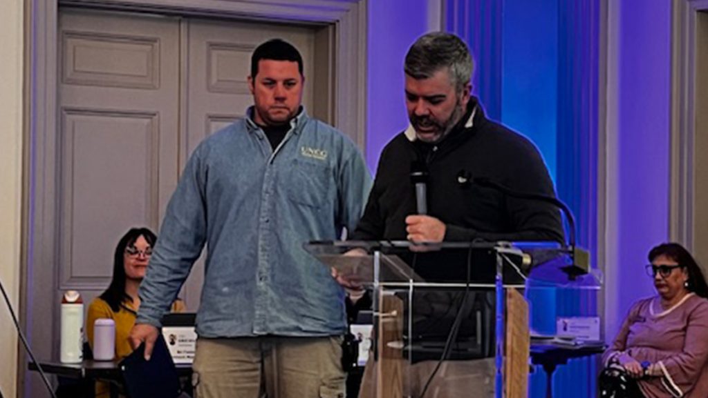 A UNCG staffmember stands by a podium.