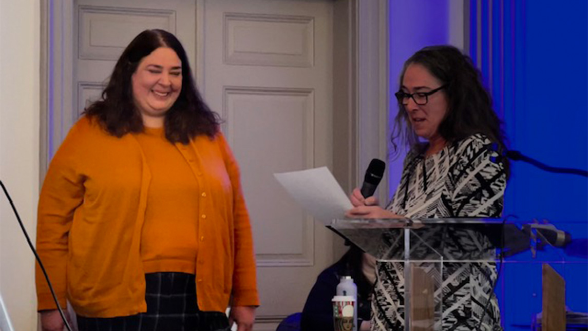 A UNCG staffmember stands by a podium.