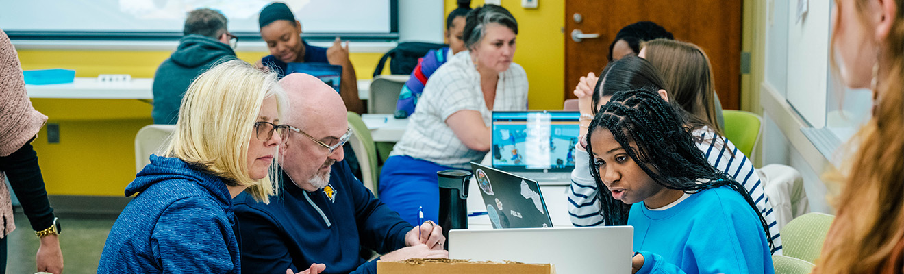 UNCG faculty sit around tables and grade student projects.