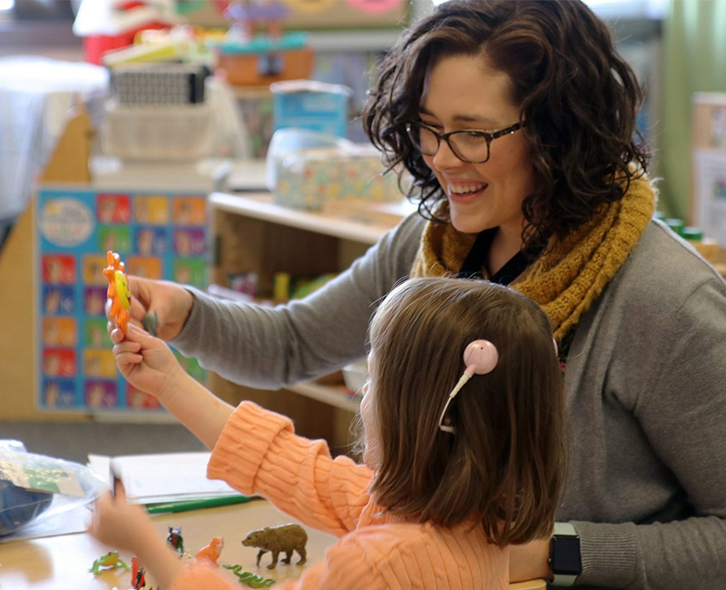 A woman plays with a child at a table.