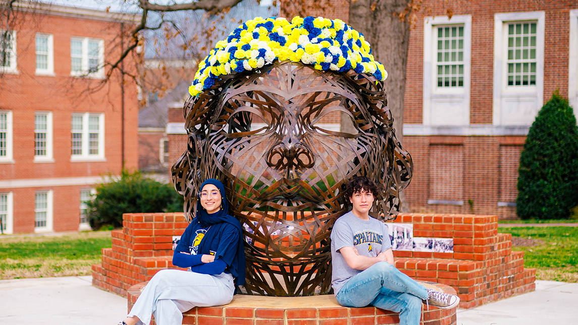 Mayar Eldeeb and Rocky Moore sit in front of a statue near the Lloyd International Honors College