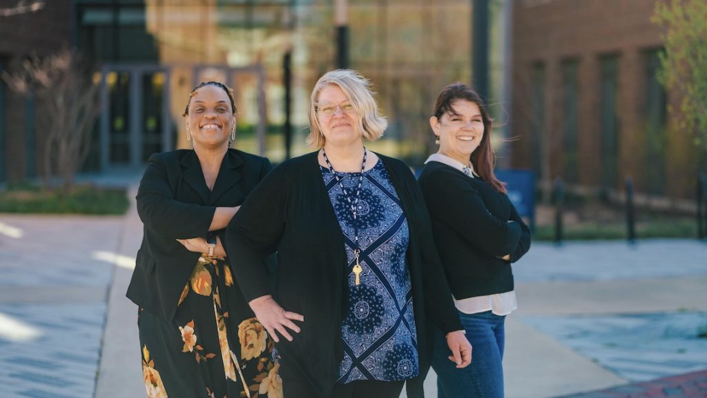 Three School of Nursing staff members standing outside of the School of Nursing building.