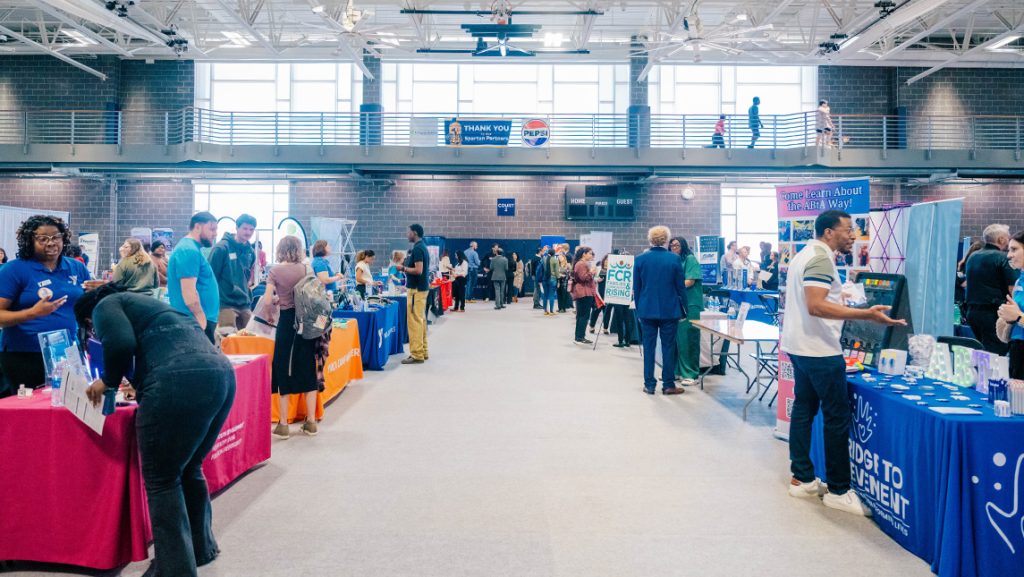 UNCG students walk around tables at career fair.