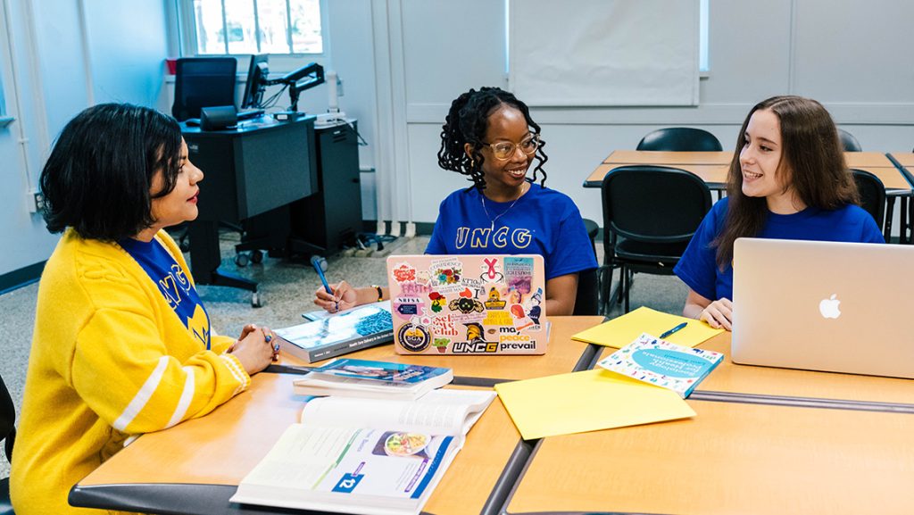 UNCG student Mary Blake Murphy asks a question at a desk.