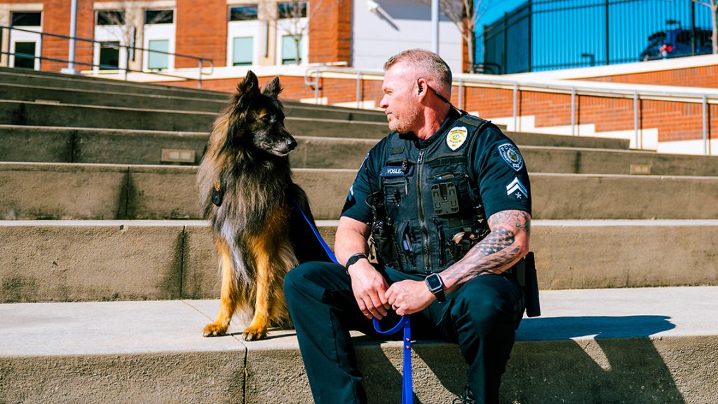 UNCG Officer Vosler sits with Odin the comfort dog.