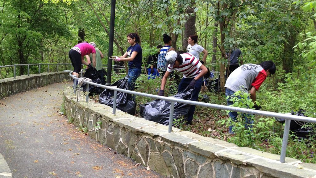 UNCG students pick up trash along walkway through Peabody Park.
