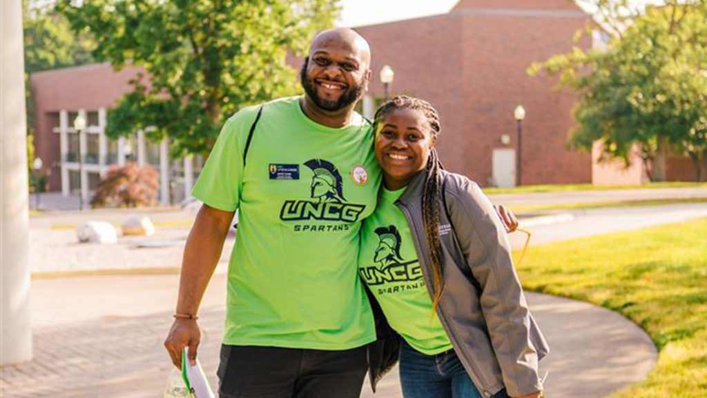 Two UNCG volunteers wearing green SOAR shirts.